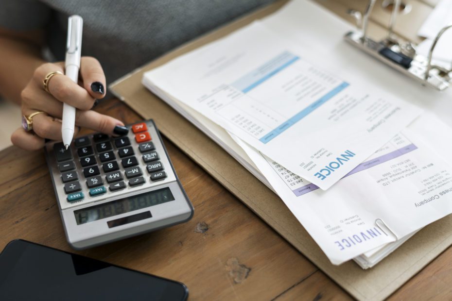 Woman doing invoice accounting on calculator